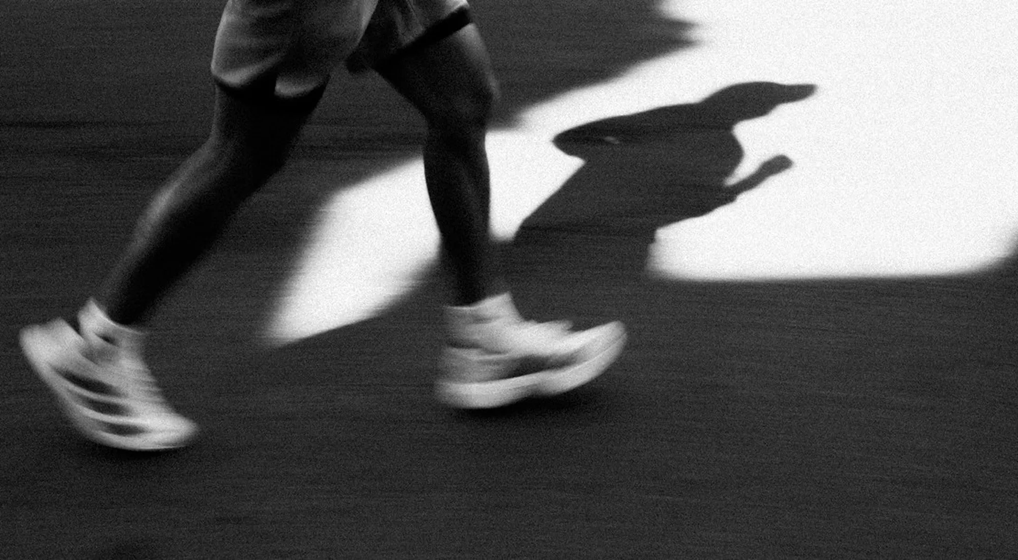 Runner mid-stride, casting a long shadow